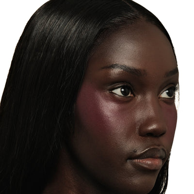 Close-up of a model's cheekbone wearing TRU SKN Soft Focus Powder Blush in Deep Violet The powder creates a natural, diffused flush with a blurred, soft-matte finish.