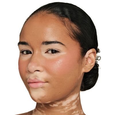 Close-up of a model's cheek wearing TRU SKN Radiant Glow Cream Blush in Soft Peach. The cheek shows a fresh, dewy, and luminous glow that melts into the skin.