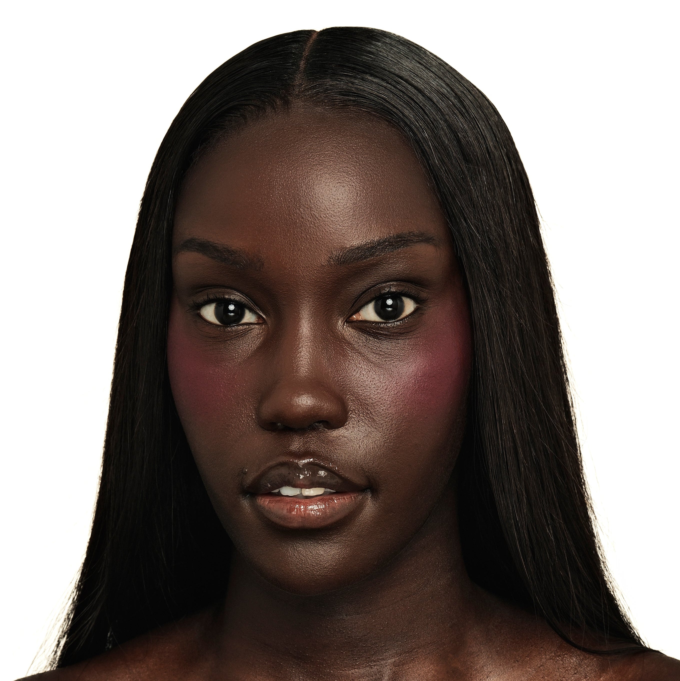 Close-up of a model applying TRU SKN Radiant Glow Cream Blush in Rich Plum. The application highlights the creamy formula melting into the skin for a deep, luminous, and dewy finish.